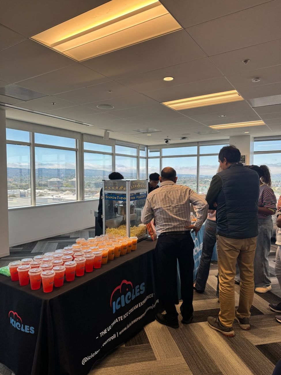 Guests gathering at an Icicles office event with popcorn and fruit drinks