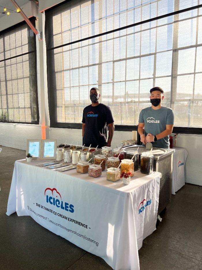 Two Icicles staff behind the catering station with the toppings bar set up