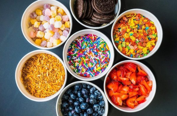 Bowls of toppings: mochi, Oreos, Fruity Pebbles, sprinkles, coconut, blueberries and strawberries